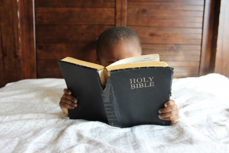 A cute boy reading an old Bible